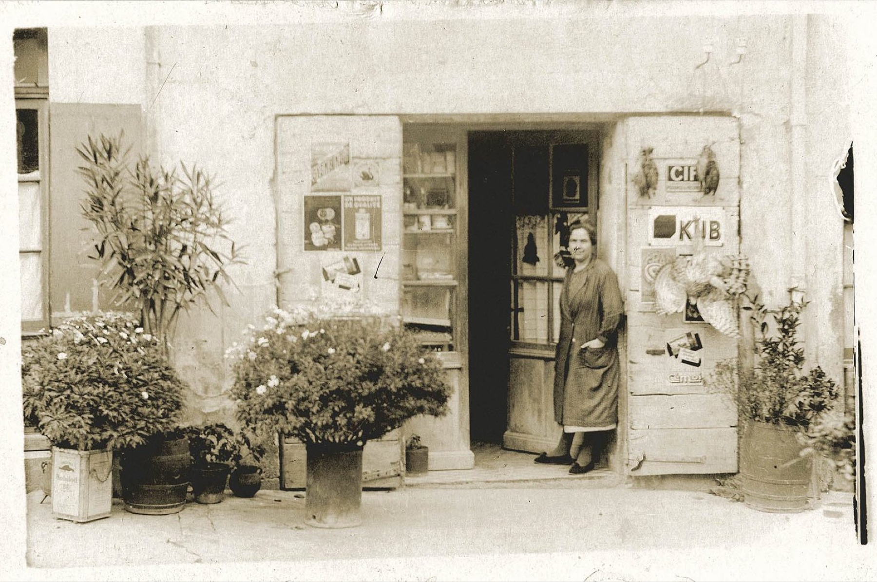 Photo d'archive sépia : l'épicerie familiale Cavet à Dieulefit dans les années 1920, Florentine sur le pas de la porte